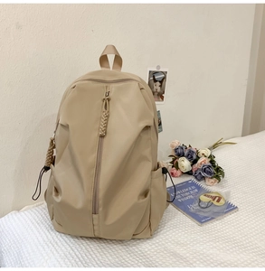 Macro detail of khaki nylon backpack featuring front zipper pocket and side storage pocket