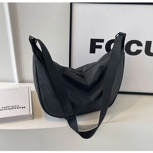 Minimalist black nylon crescent bag with adjustable wide strap on a clean white display