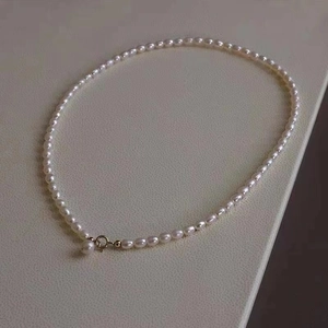 Elegant natural freshwater pearl necklace with gold clasp on a beige leather background