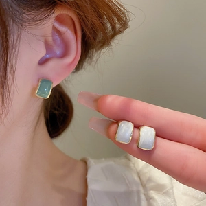 Close-up of French vintage gold geometric stud earrings in mint green and cream white