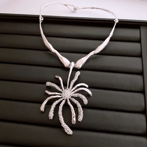 Détail du pendentif fleur vintage argenté avec strass sur présentoir noir
