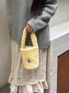 Detail of yellow sherpa bucket bag with cute black cat patch and soft plush handle