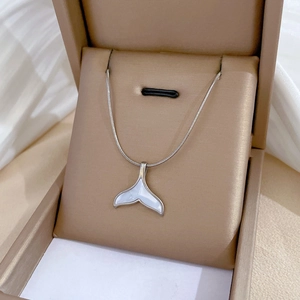 Détail d'un collier queue de poisson argenté avec pendentif nacre dans un coffret cadeau