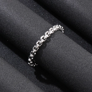 Macro shot of silver chain-textured stainless steel ring on a dark pedestal