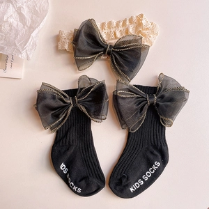 Detail of baby socks and headband set with oversized black organza bows and gold trim