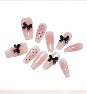 Detail of pink gradient coffin nails with 3D black bows and classic polka dots