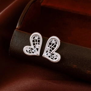 Détail macro de la boucle d'oreille cœur en argent avec maille creuse et zircons brillants