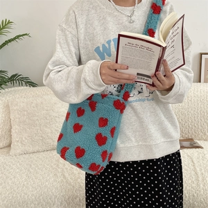 Blue plush tote bag with red hearts pattern in a lifestyle fashion scene