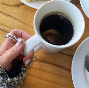 Minimalist 925 sterling silver twisted rope ring shown on hand with coffee cup background