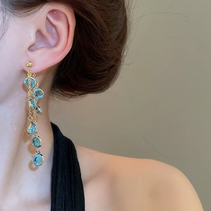 Dettaglio di orecchini a frangia lunga placcati in oro 18k con perle in vetro celeste