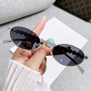 Occhiali da sole ovali in argento con ponte in strass e stanghette nere ondulate