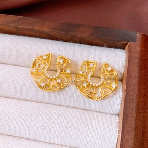 Macro detail of gold geometric hollow earrings with zircon inlay in a jewelry box