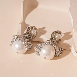 Detail of baroque pearl earrings with rhinestones on a decorative plaster base