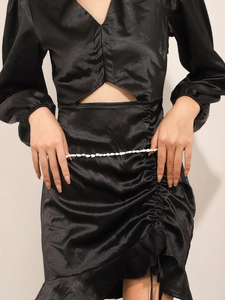 Detail of waist cut-out on black satin dress with white shell decorative body chain