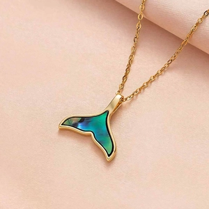 Macro view of gold whale tail pendant with gradient blue shell inlay on fine chain