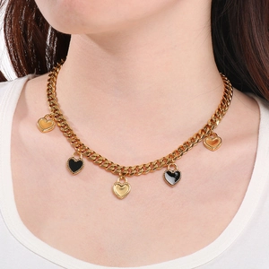 Gros plan d'un collier chaîne cubaine plaqué or 18K avec pendentifs en cœur émaillé
