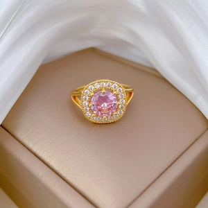 Macro detail of golden ring with round pink gemstone and pavé diamonds on silk