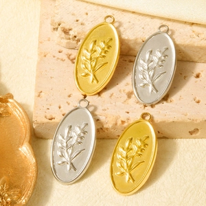 Macro shot of gold and silver stainless steel oval pendants with olive branch relief pattern
