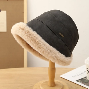 Détail d'un bob d'hiver en daim noir avec bordure en peluche beige et logo en métal