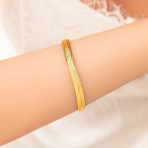 Flat 18k gold plated stainless steel snake chain bracelet worn on a female wrist