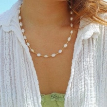Detail shot of a double-layered natural pearl and turquoise necklace on model