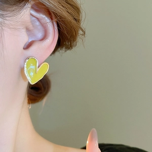 Gros plan d'un mannequin portant une puce d'oreille cœur jaune brillant à bord doré