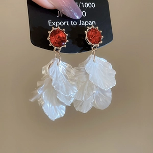Detailed macro of crystal pearl tassel earrings with red gemstone and white petals