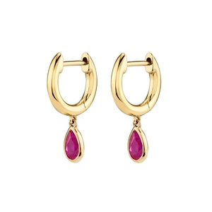 Close-up of golden hoop earrings with teardrop red zircon pendants on white background