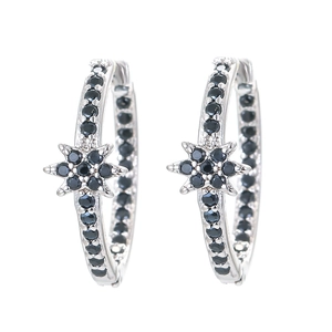 Detail of silver hoop earrings with black zircon pavé and a central hexagram star motif