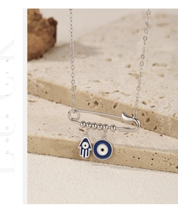 Macro detail of silver paperclip necklace with Hamsa hand and Evil Eye charms