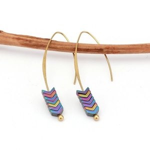 Detailed view of bohemian gold drop earrings with colorful V-shaped hematite beads on wood