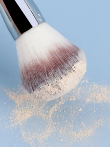 Macro shot of dual-ended makeup brush showing soft gradient bristles with loose powder