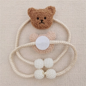 Detail of plush bear curtain tiebacks with pearl accents and gold braided cords