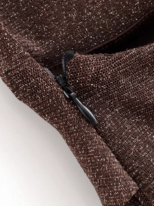Dettaglio macro del tessuto a maglia glitter marrone scuro con cerniera invisibile nera