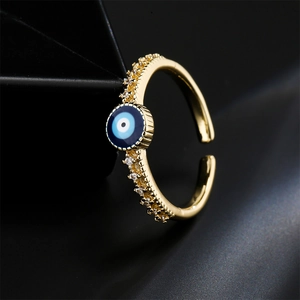 Gold plated evil eye open ring with shimmering pavé zircon stones on a dark background