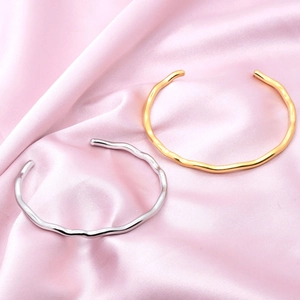 Minimalist wave-textured open bangles in polished gold and silver finishes on silk