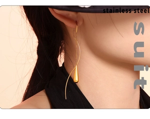 Close-up of golden stainless steel teardrop tassel earrings worn by a model