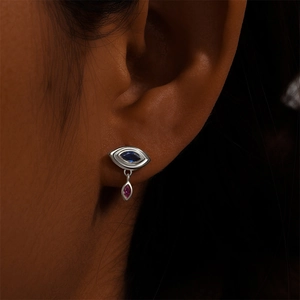Close-up of eye-shaped silver earring with blue marquise stone and pink teardrop gem