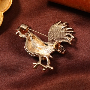 Detailed back view of a rooster brooch showing secure safety clasp and gold finish