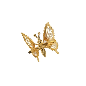 Golden metal butterfly hair clip with hollow wings and moving parts on white background
