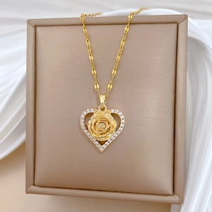 Detailed close-up of a gold heart pendant with rose design and sparkling zircons