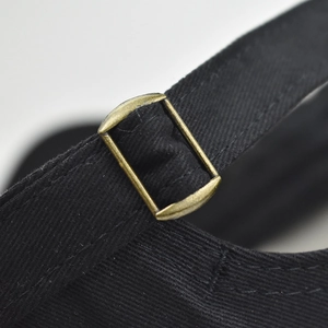Detailed macro view of the black cotton baseball cap with antique bronze metal buckle