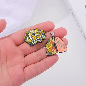 Broches émaillées cerveau et poumons avec détails floraux colorés tenues en main