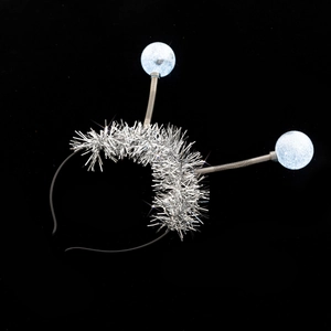 Close-up of silver tinsel headband featuring blue spring antennas against a dark background