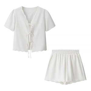 Detail of white two-piece summer set showing V-neck ties and ruffled wavy edges