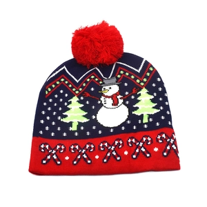 Detail of Christmas knit hat featuring snowman, tree patterns and a red pompom