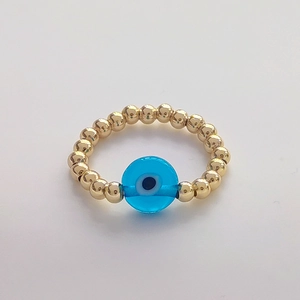 Macro view of golden beads and blue evil eye charm on a handcrafted bohemian ring
