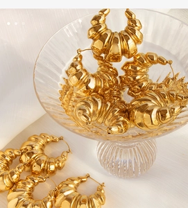 Close-up of gold chunky textured hoop earrings displayed in a clear glass bowl