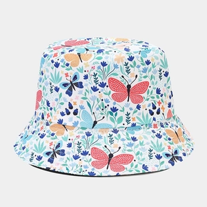 Detail of canvas bucket hat featuring colorful butterfly and floral print on white fabric