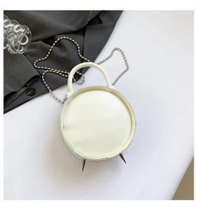 Detailed top view of white round crossbody bag with silver ball chain and metal spikes